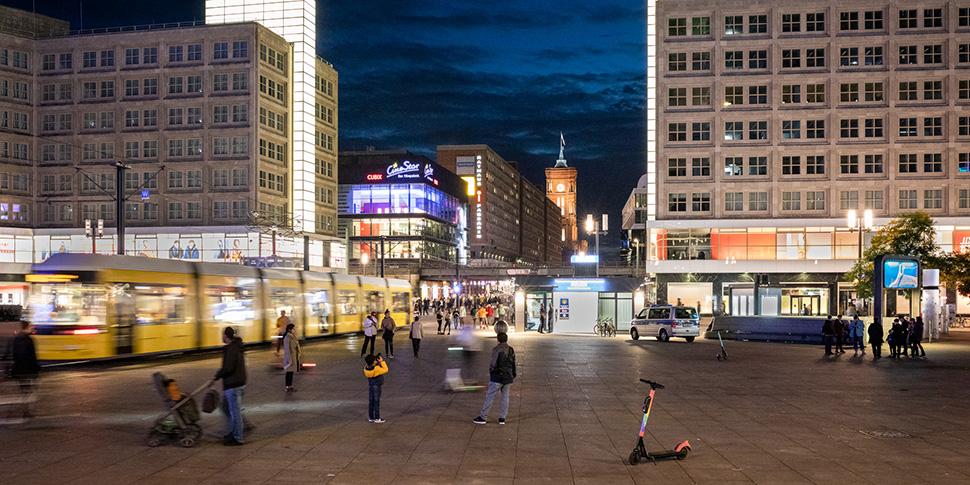 Blick auf den Berliner Alexanderplatz am Abend mit Tram, Fußgängern und Leuchtreklame