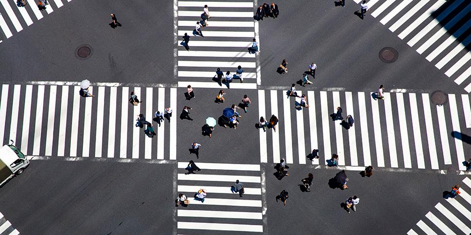 Vogelperspektive auf eine Kreuzung mit Zebrastreifen und Menschen.
