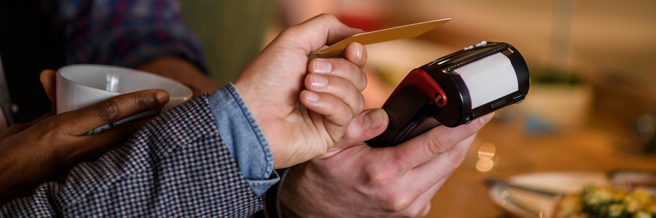 Man paying with mobile phone in coffee shop.