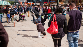 Eine Menschengruppe auf dem Berliner Alexanderplatz steht um eine Gruppe Breakdancer und beobachtet die Performance