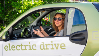 Eine junge Frau sitzt in einem elektrischen Smart.