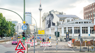 Berlin, Germany - September 12, 2013: Urban scene in Prenzlauer Allee street in Berlin with mural from the project Wrinkles of the city by artist JR, Tv tower and traffic