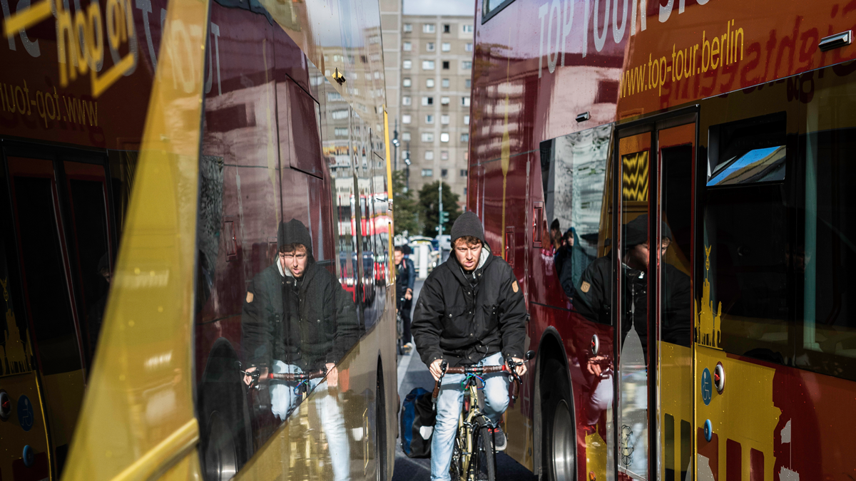 ASCT, News: RealLabHH, Sichere Mobilität Ein Mann auf einem Fahrrad fährt durch eine sehr schmale Lücke zwischen zwei Bussen.
