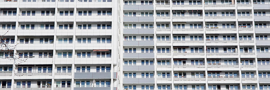 weiß-graue Hausfassade eines Wohnblocks in Berlin mit Fenstern und Balkonen