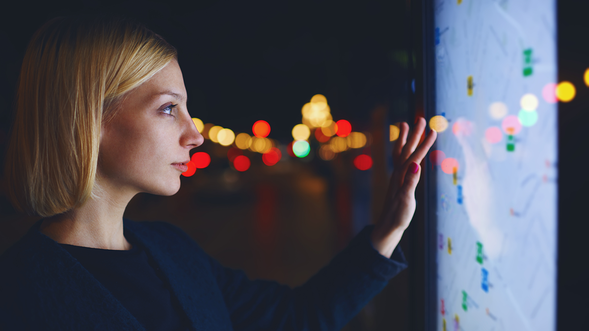 DPS, News: Integration von Piveau in CIVITAS/CORE Young female tourist using smart city gadget to get direction in Barcelona central, female in night city standing front big digital screen with city map routes and locations shown on it,filtered image
