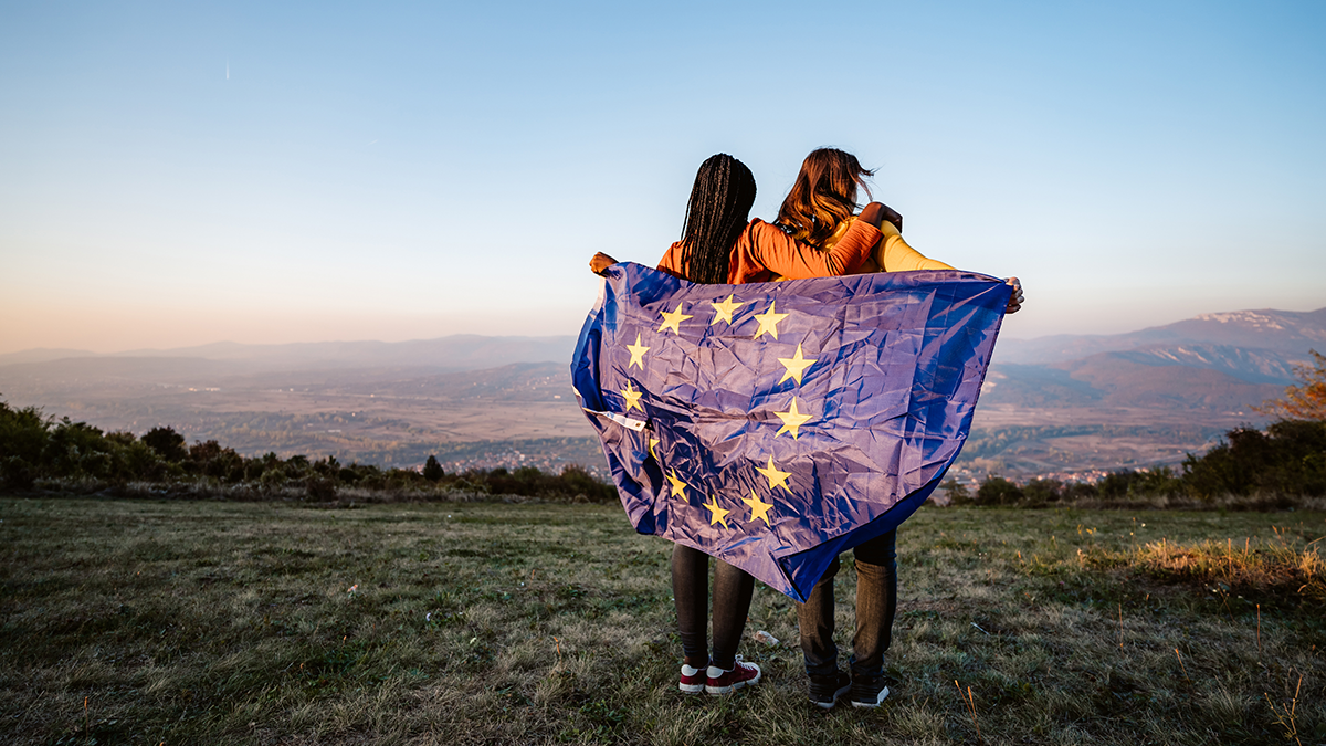 DPS, Projekte: Data.Europa.EU Two young multi-ethnic women holding European Union flag on meadow.
