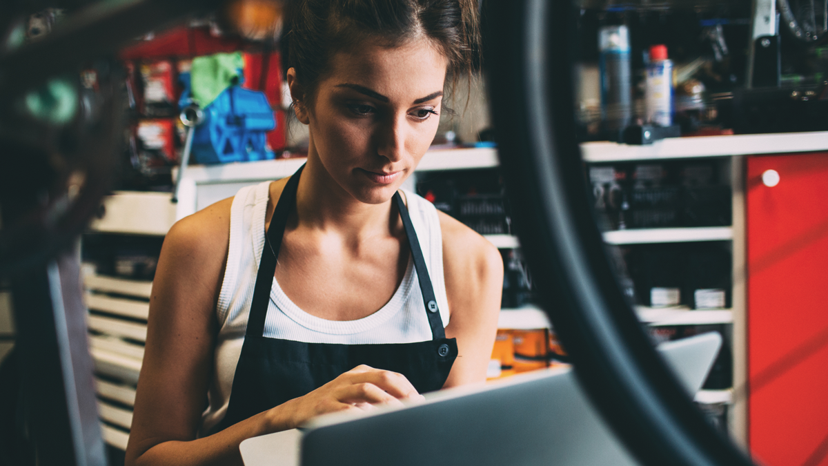 Porträt einer jungen Mechanikerin, die einen Laptop benutzt.