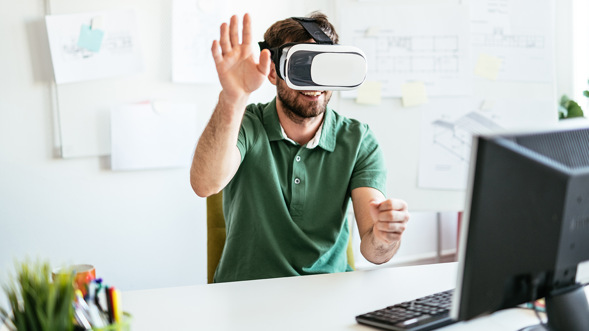 DPS, News: Virtual Reality Check Mann mit VR-Brille sitzt im Büro und gestikuliert