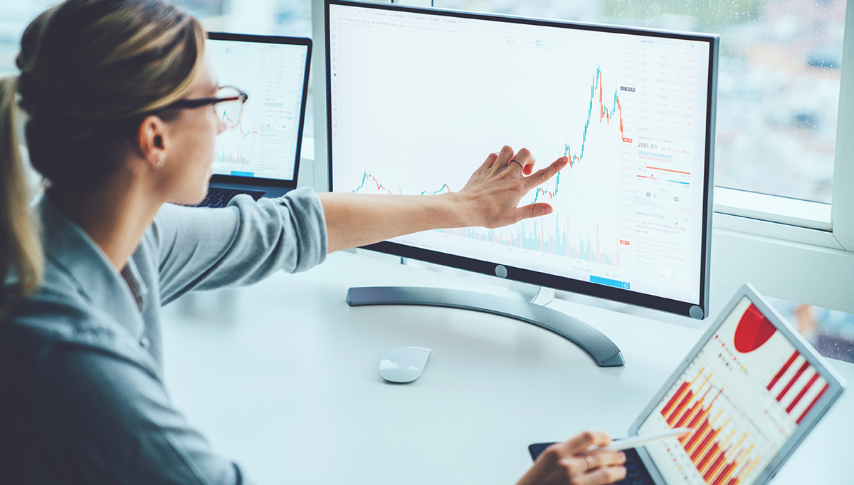Business woman study financial market to calculate possible risks and profits.Female economist accounting money with statistics graphs pointing on screen of computer at desktop. Quotations on exchange
