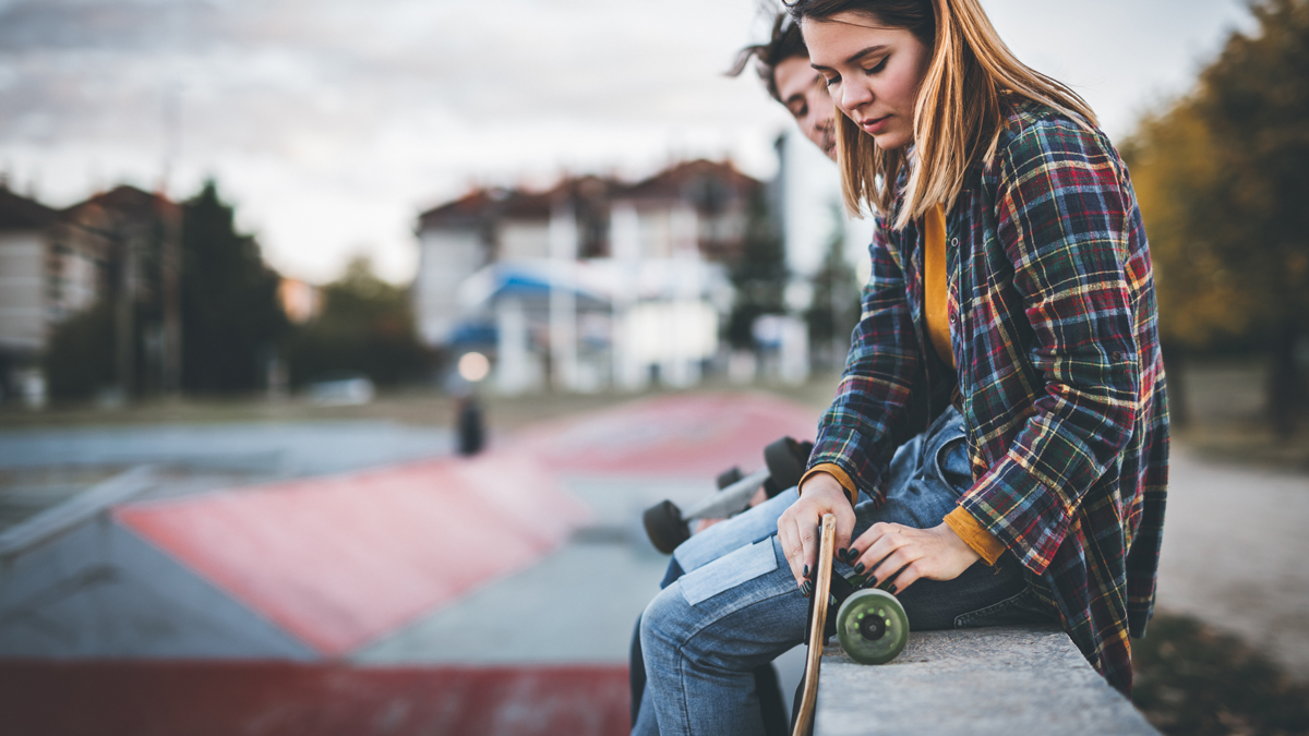 Young skateboarders sitting on concrete and taking a rest from ride.