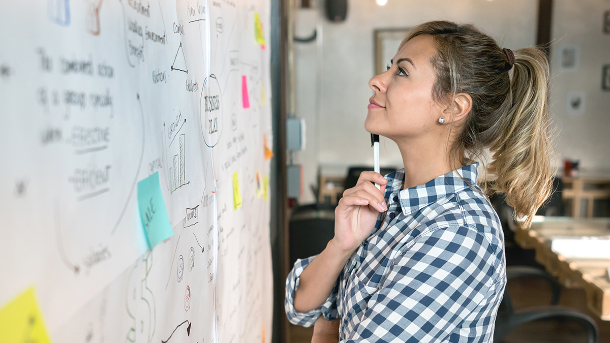 DPS, Projekte: Mobilisierungspotenziale Eine Frau steht nachdenklich vor einer Workshop-Pinnwand und sieht sich die Mindmap an