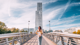 Tourist girl walking by footbridge in MediaPark in Cologne city - it is a popular and modern district with pond, futuristic skyscrapper with media companies