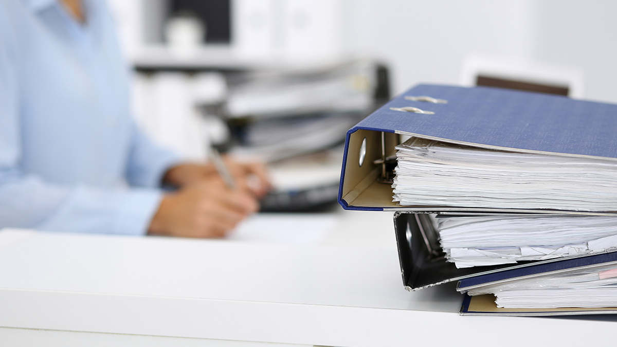 DPS, Projekte: Registermodernisierung Calculator and binders with papers are waiting to be processed by business woman or bookkeeper back in blur. Internal Audit and tax concept.