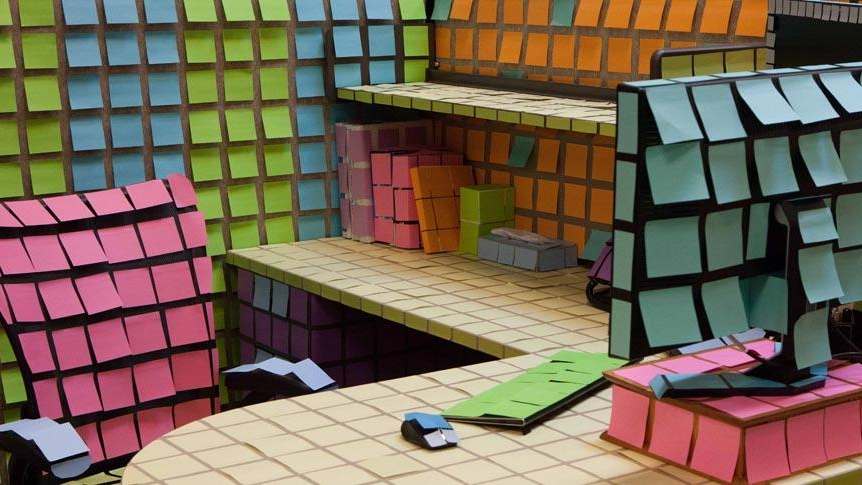 Büroarbeitsplatz mit verschiedenen bunten Post-its beklebt