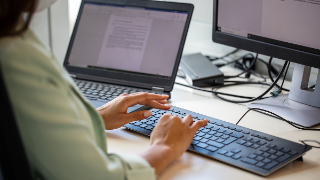Close-up of woman typing on computer keyboard at workplace. Businesswoman using desktop computer in office.