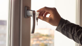 Ein Fenster wird mit einem Schlüssel gegen Einbruch gesichert.