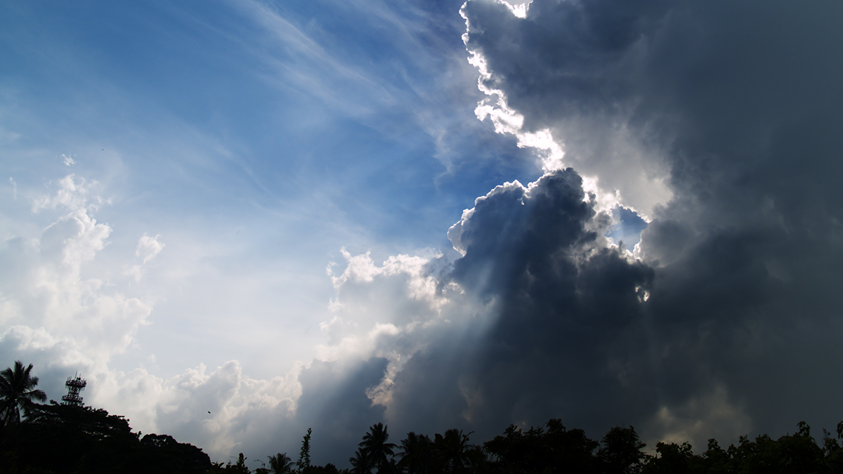 Tropical mid morning storm gathering rapidly amidst the bright sun in a clear blue sky