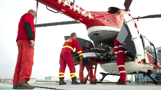 Rettungshubschrauber auf dem Dach des Unfallkrankenhaus Marzahn in 4 Sanitäter einen Patienten auf einer Trage verladen