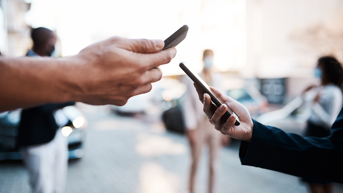 SQC, DPS, Projekte: IDS International Data Spaces Shot of two unrecognisable people using Covid-19 tracking apps on their smartphones in the city