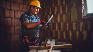 Ein Arbeiter auf einer Baustelle benutzt ein Tablet.