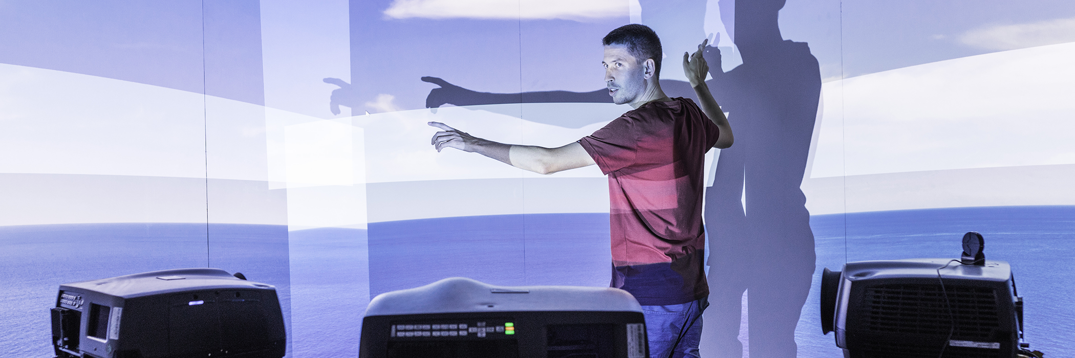 Ein Mann steht vor einer gekrümmten Projektionsfläche im  Computer Graphics and Visualization Lab bei Fraunhofer FOKUS