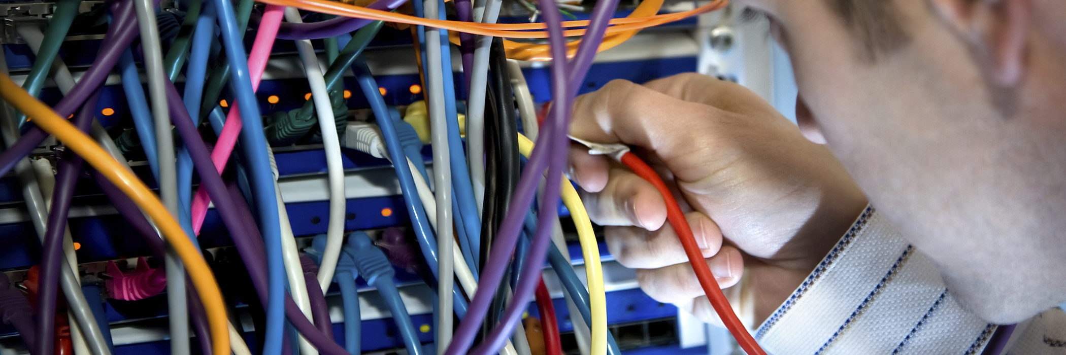 IT Technician With Server Cables: IT technician working at network server computers