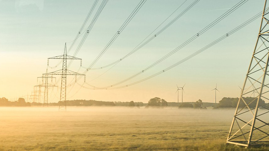 Hochspannungsleitung bei Sonnenaufgang und Morgennebel