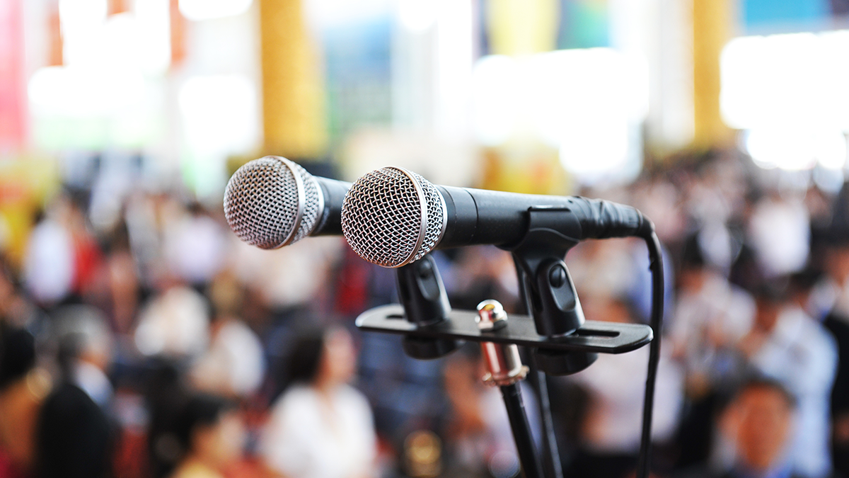 SQC, News: IKT-Vortrag Closeup microphone in auditorium with people.