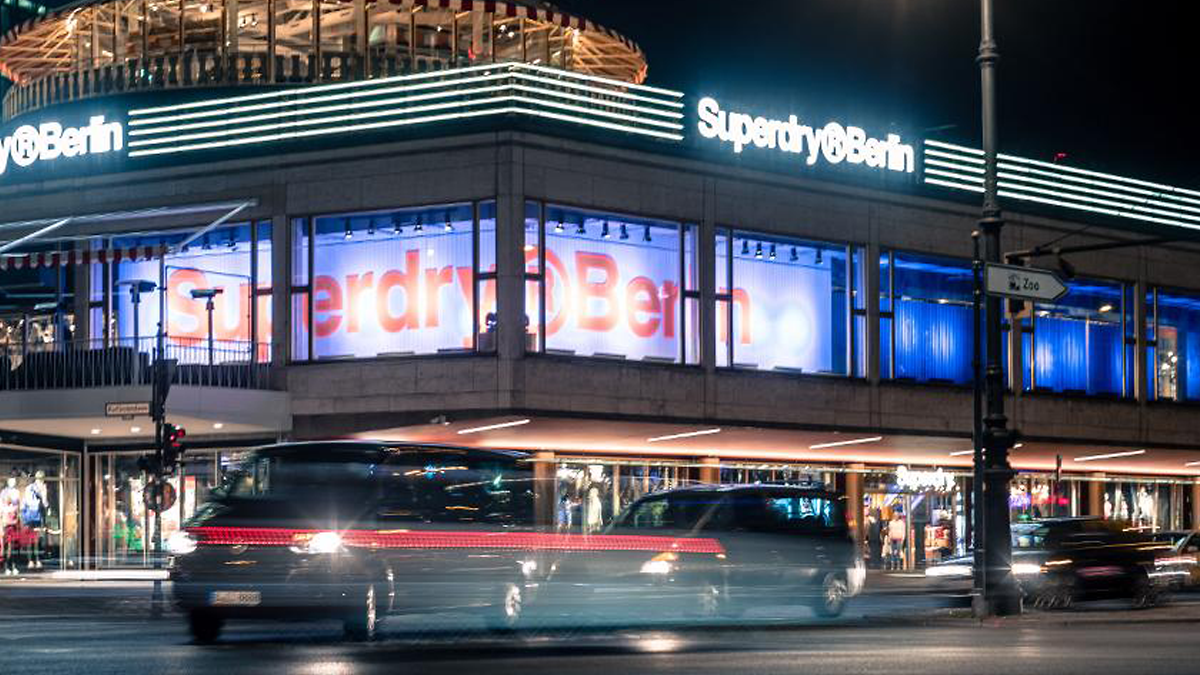 SQC, News: Urban Mobility Der Superdry Berlin von draußen bei Nacht neben einer befahrenen Straße