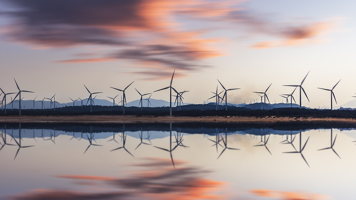 Windkraftanlage und Stromtürme bei Sonnenuntergang