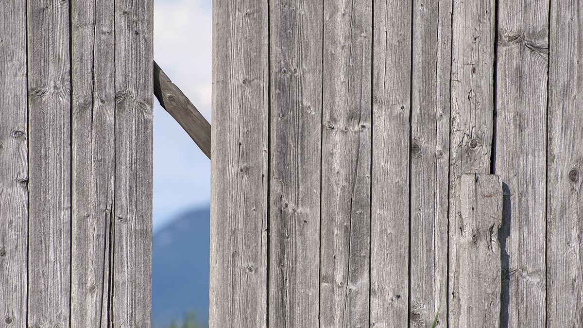 SQC, Technologien: Fuzzing, Testing Image of a wooden fence with a missing a post with a diagonal plank in the back and offering a see through opening to the mountain area in the background.