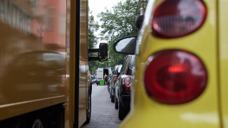 Zwei Lieferfahrzeuge parken in einigem Abstand zueinander in zweiter Reihe neben vielen parkenden Autos