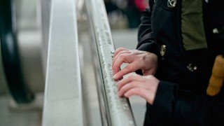 Eine blinde Person liest Informationen an einem Geländer am Berliner Hauptbahnhof in Braille-Schrift