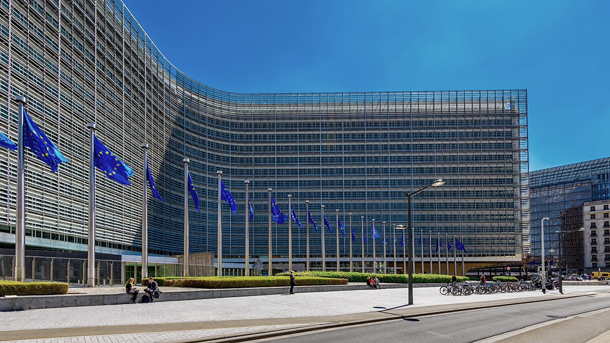 Gebäude des EU Parlaments in Brüssel mit einer Reihe von EU Flaggen 