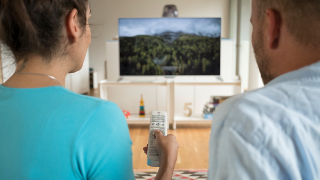 FAME, News: DVB-I Pilot Zwei Personen schauen auf einen Fernseher und benutzen eine Fernbedienung.