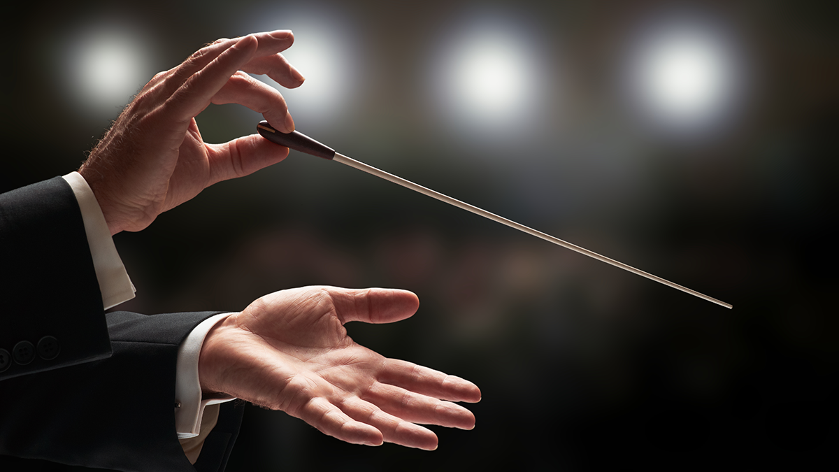 Conductor conducting an orchestra with audience in background