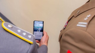 Ein Smartphone in der Hand eines Menschen, das die Oberfläche des Projekts KI in LMS zeigt.