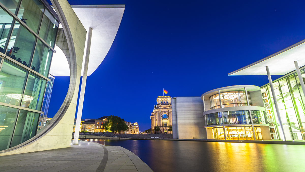 Mighty Reichstag (1894) and government buildings including Bundeskanzleramt the German chancellery illuminated at night and reflected in the river Spree, Berlin, Germany.