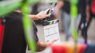 Filming on location. Man holding a clapperboard in front of the camera, the filming process. Scene on location