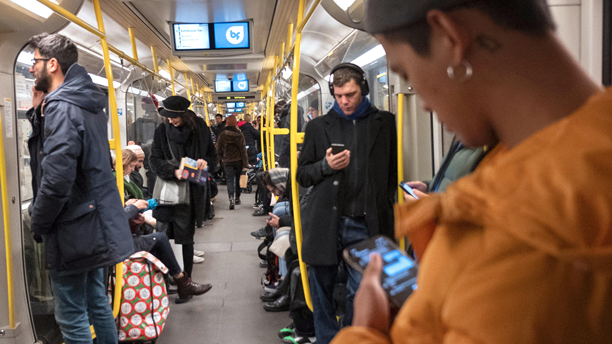 Menschen in der Berliner U-Bahn nutzen verschiedene mobile Endgeräte