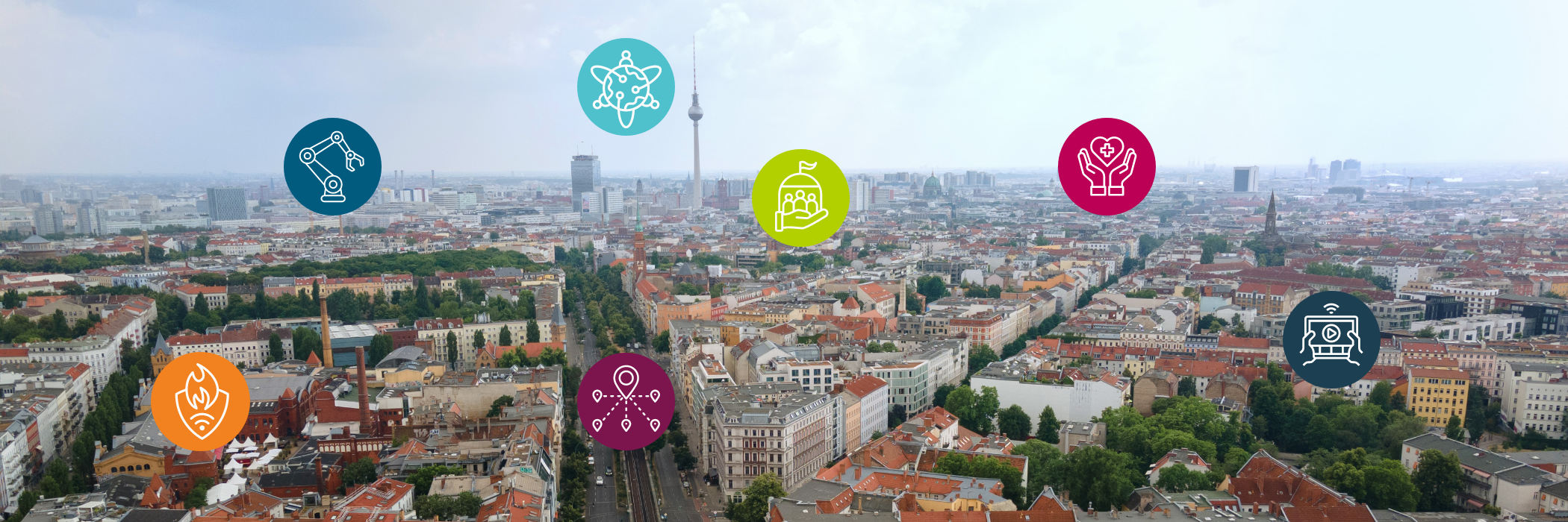 Luftaufnahme Berlin aus Nordwesten Richtung Berlin-Mitte und Alexanderplatz, darauf platziert sind 7 Icons, die die Anwendungsfelder von Fraunhofer FOKUS repräsentieren