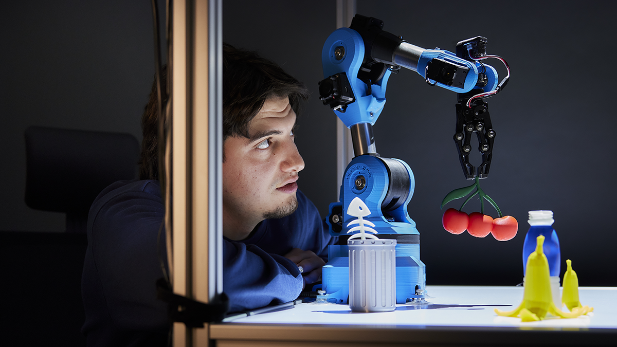 Researcher working with a 3D-printed robot arm moving different 3D-printed objects