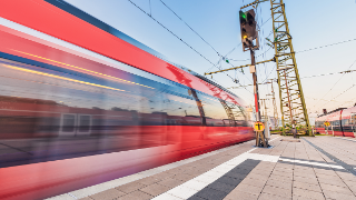 High speed train in motion on the railway station at sunset. Red blurred modern intercity train on the railway platform in Europe. Passenger railway transportation. Railroad in the evening. Travel