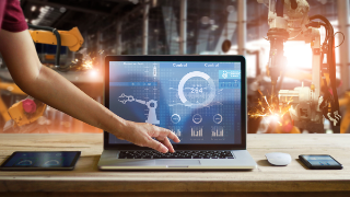 Engineer touching laptop to check and control welding robotics automatic arms machine in intelligent factory automotive industrial with monitoring system software. Digital manufacturing operation.Industry 4.0